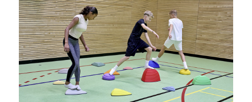 Kinder auf bunten Flusssteinen in Sporthalle