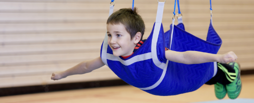 Kind in blauer Turnschaukel im Sportunterricht